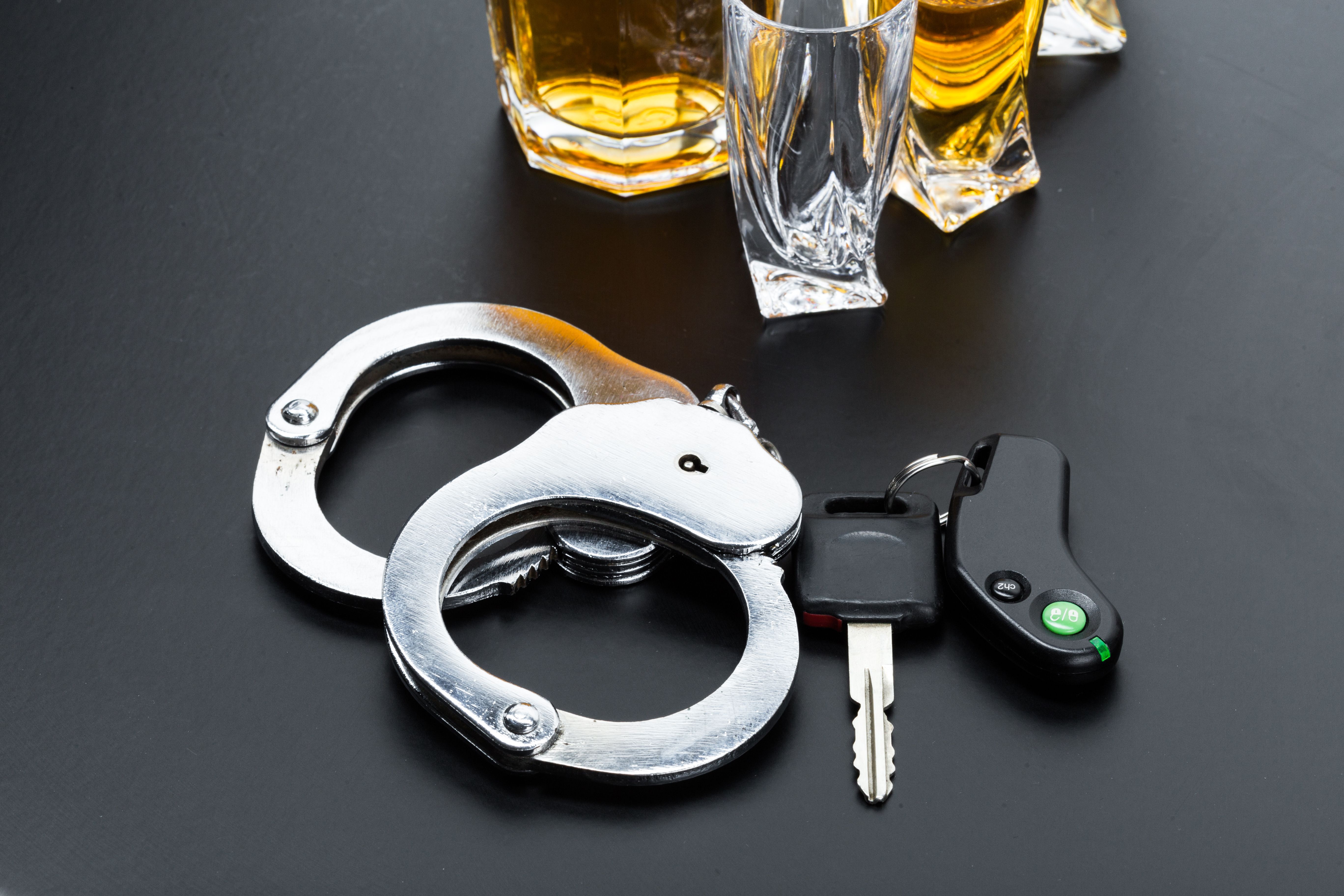 Handcuffs, car keys and alcohol on a table